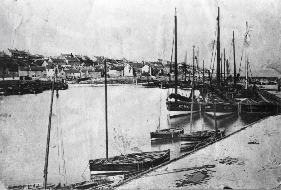 Black and White photo of Buckhaven Harbour in Snow with fishing boats moored and the town in the background