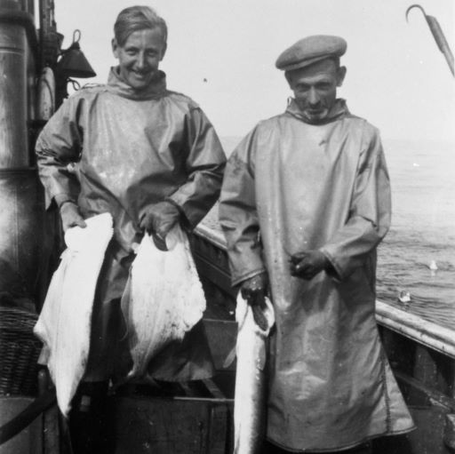 Archive image of two men on board a boat holding fish